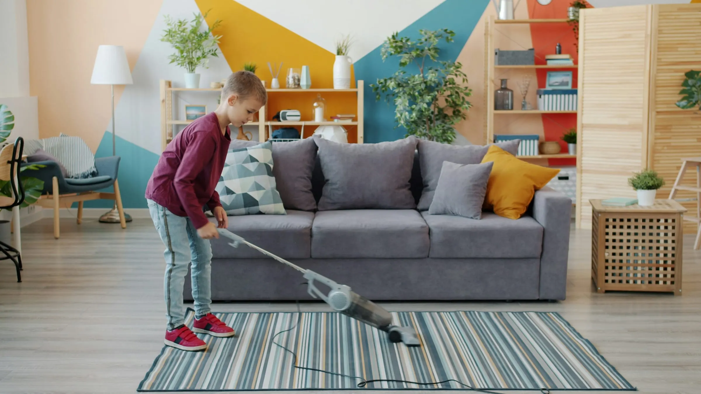 Boy vacuuming a striped rug in a bright living room