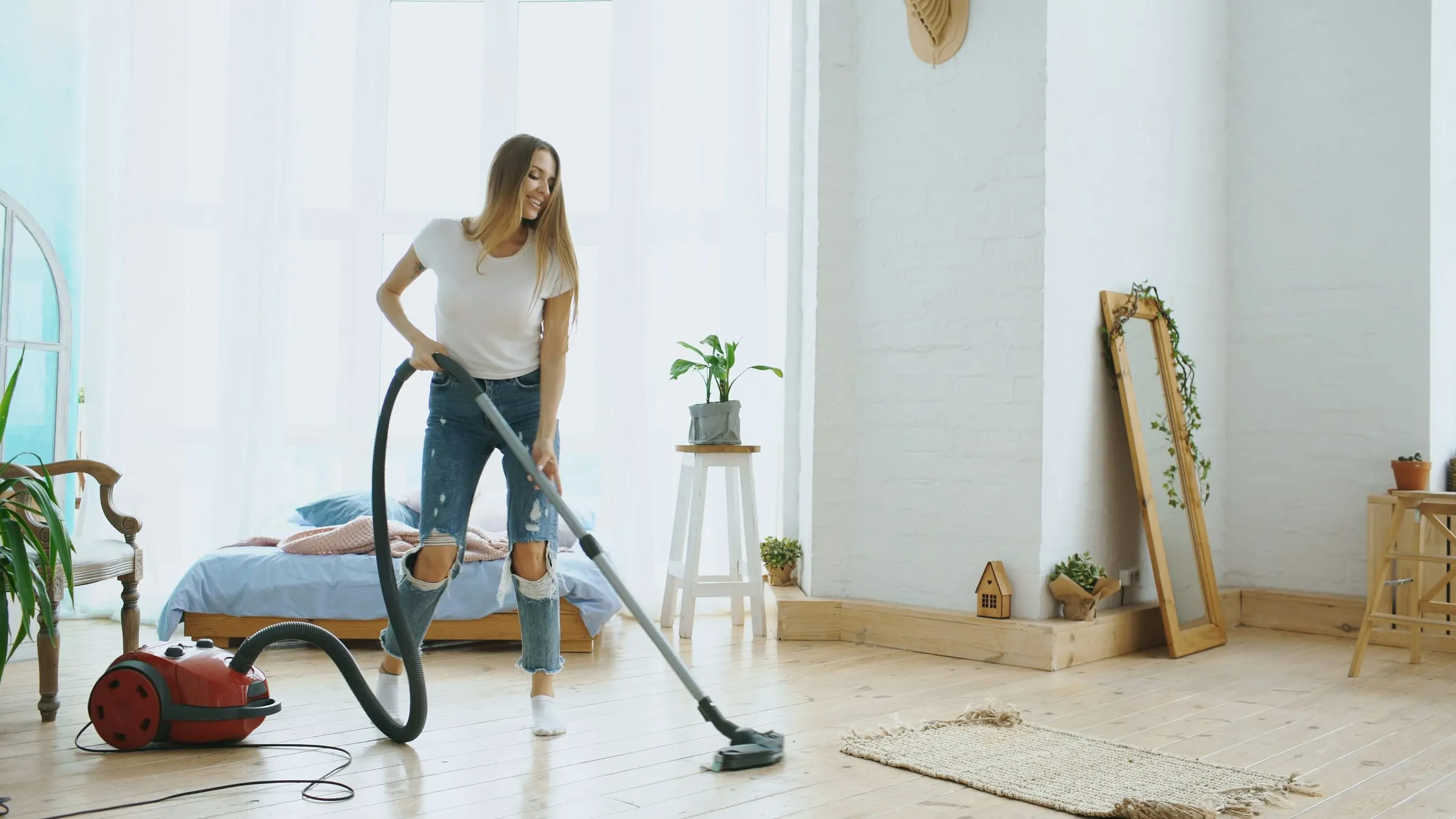 Woman using a cylinder vacuum cleaner in a bright room