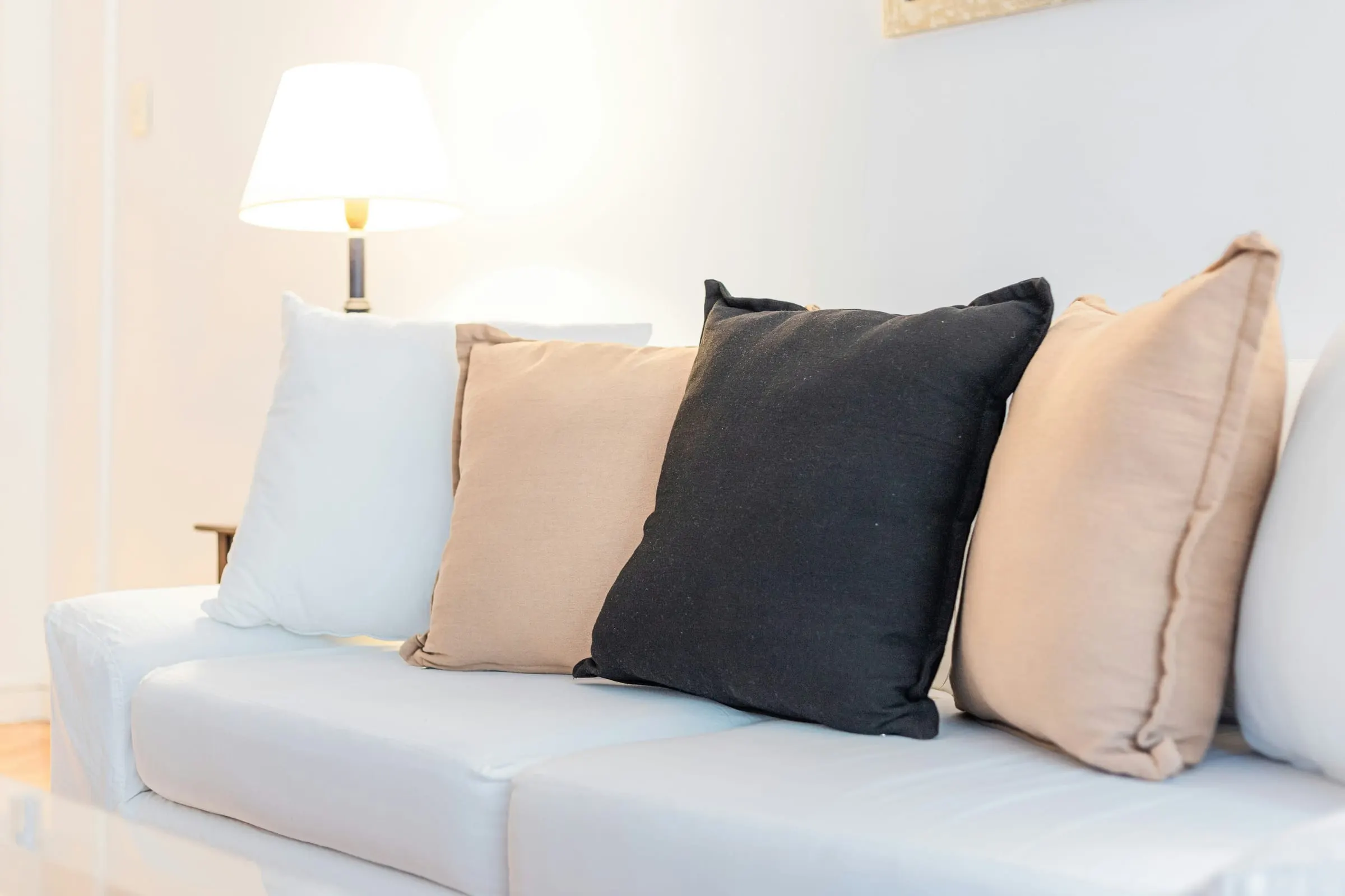 White fabric sofa with cushions beside a lamp